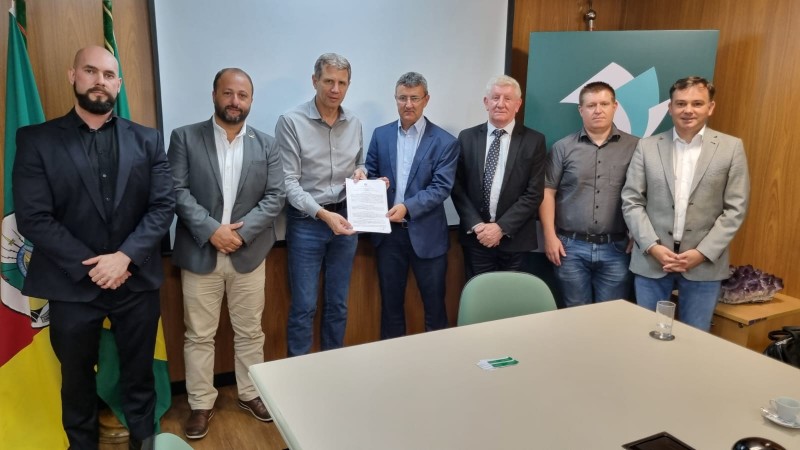 Secretário, presidente da COTRIFRED e diretores mostram termo para expansão da indústria de laticínios assinado.