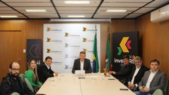 Foto com várias pessoas sentadas no entorno de uma mesa