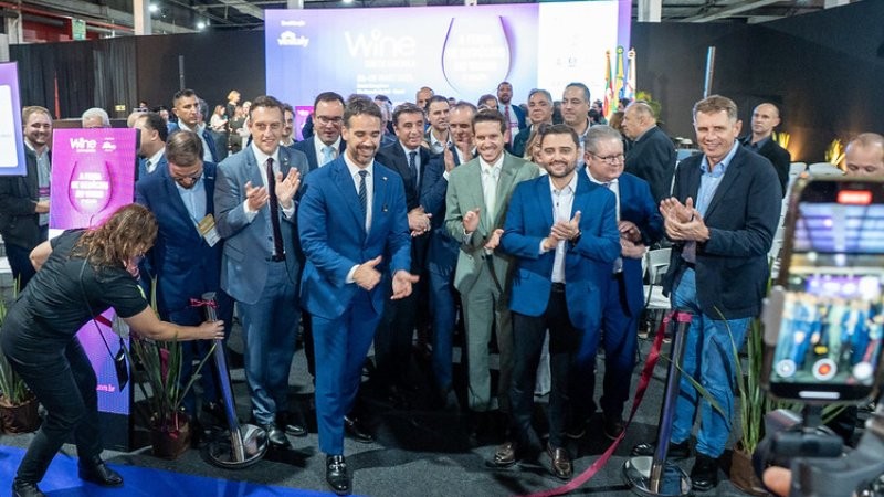 Grupo de homens aplaudem ao descerrar faixa de abertura do evento