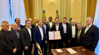 Grupo de homens posa para a foto com o homem ao centro segurando um documento