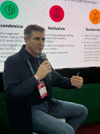 Foto do secretário Ernani Polo - um homem branco, de calça jeans e casaco preto - segurando um microfone. 
