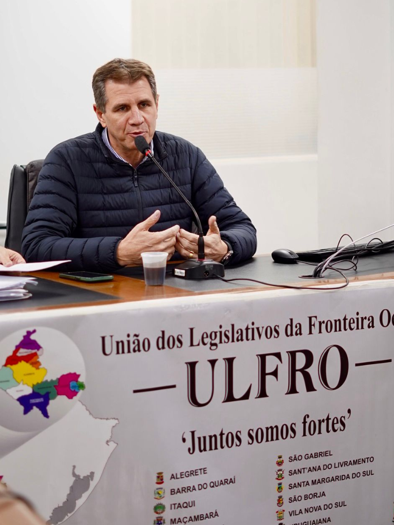 Homem fala ao microfone de mesa