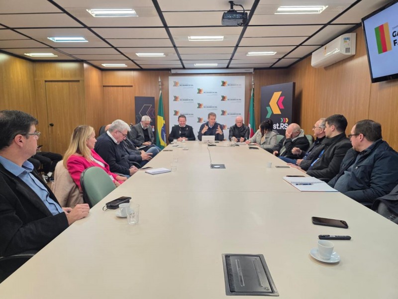 Uma grande mesa bege com diversas pessoas sentada ao redor
