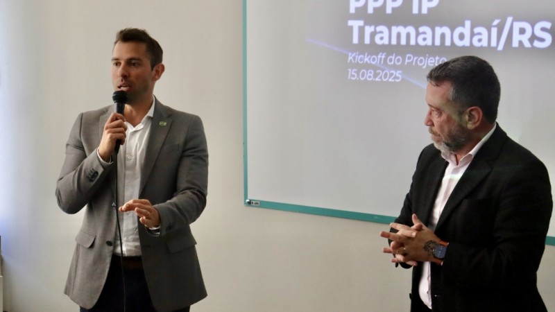 Imagem de dois homens brancos palestrando. Um segura um microfone.