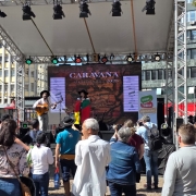 Músicos se Apresentam num palco externo com público assistindo