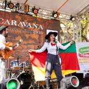 Músicos se apresentam em palco externo, artista segura a bandeira do Rio Grande do Sul