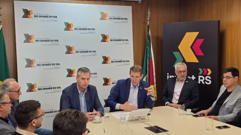 Mesa de reuni&atilde;o com diversos homens sentados ao redor