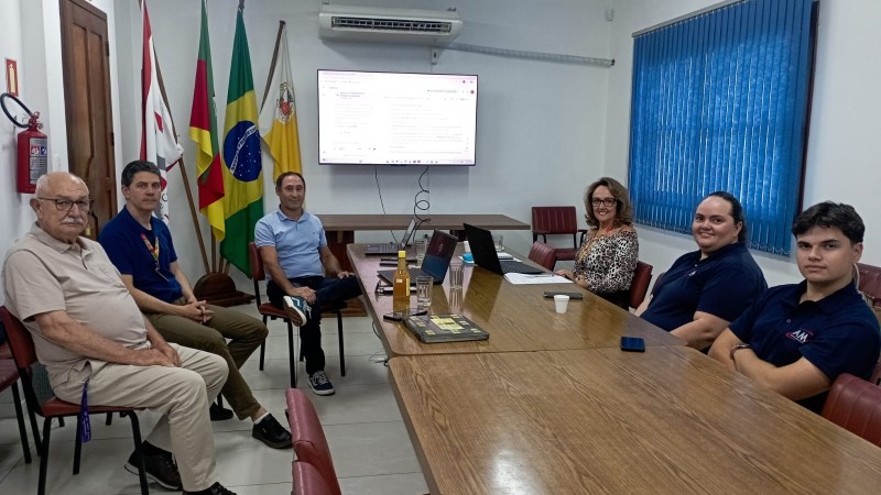 Grupo de pessoas sentada em torno de uma grande mesa de reuni&otilde;es