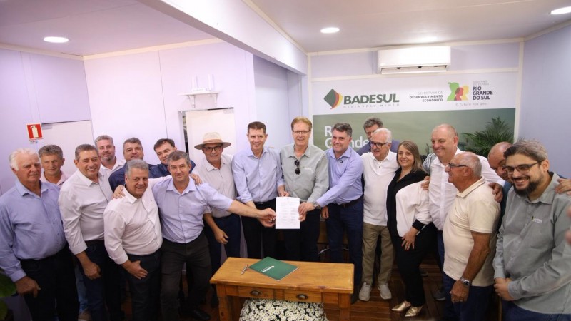 Grupo de pessoas de p&eacute;, posando para a foto. Alguns seguram um documento. 