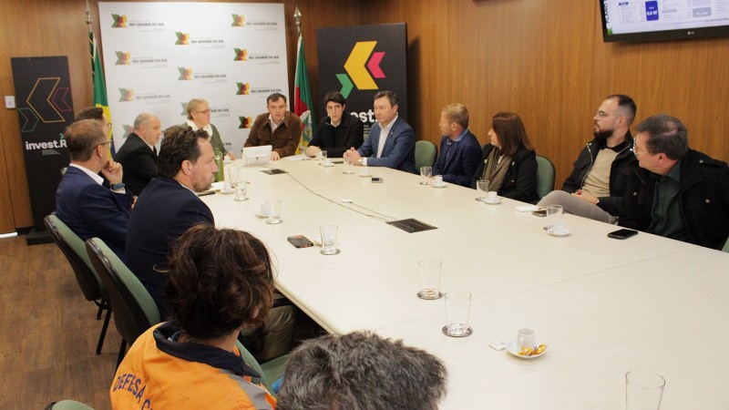 Foto de um grupo de pessoas ao redor de uma mesa de reuni&otilde;es